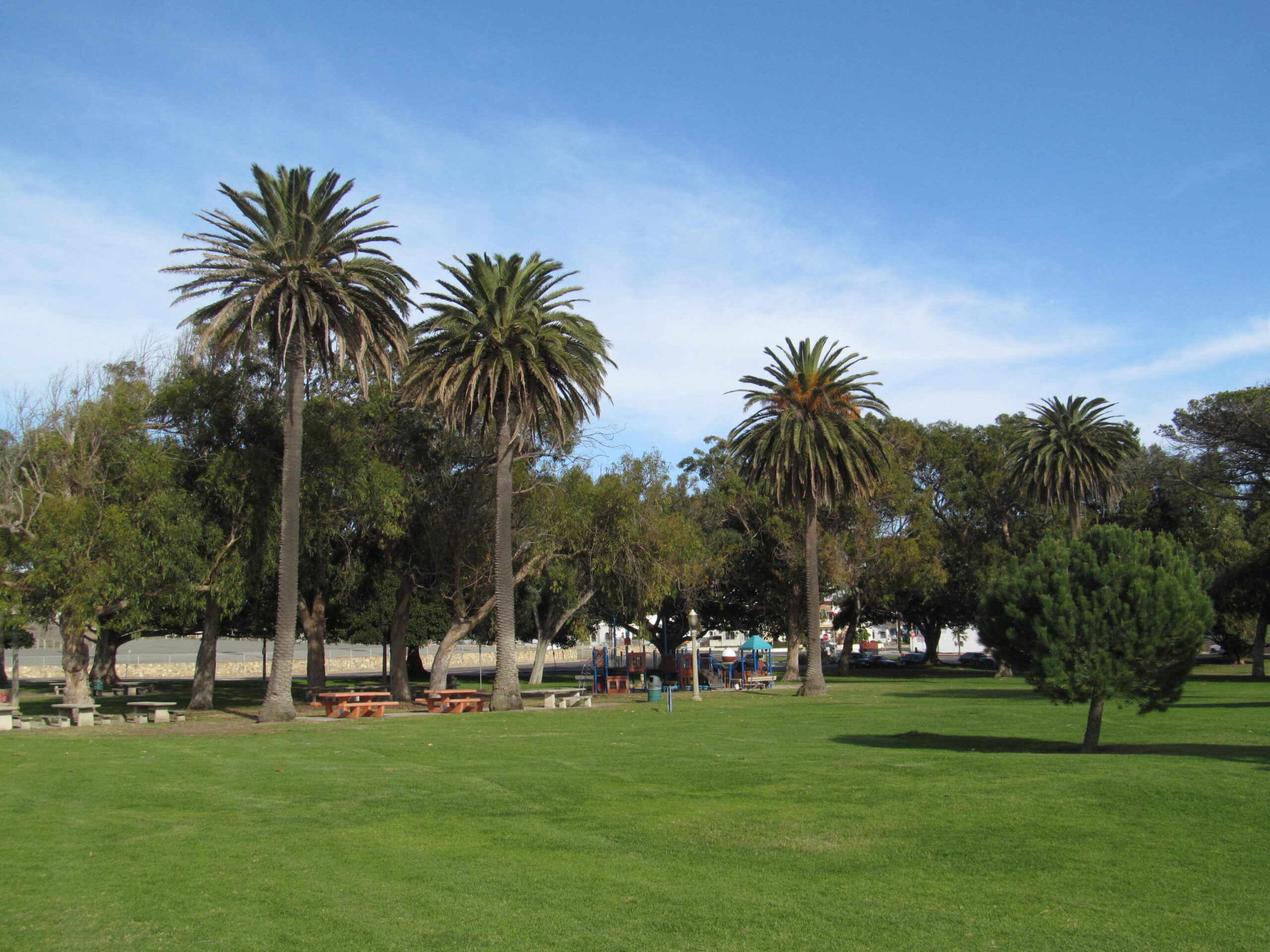 Point Fermin Lighthouse, with a green lawn, palms, and other trees. Credit: Wikimedia